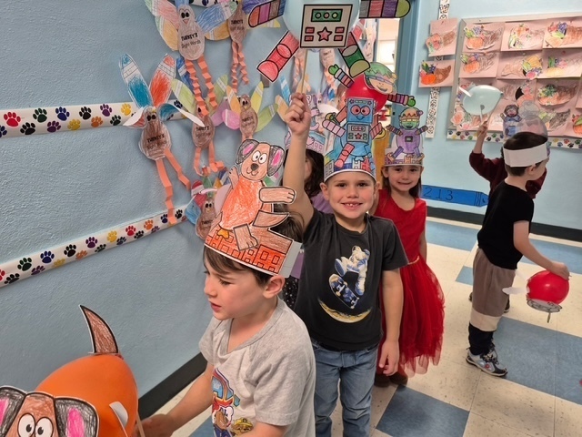 students holding baloons decorated as creatures and walking down the school hallway