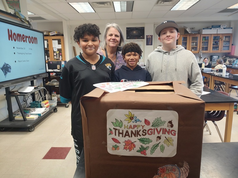 three boys and woman pose with thanksgiving decorated box.
