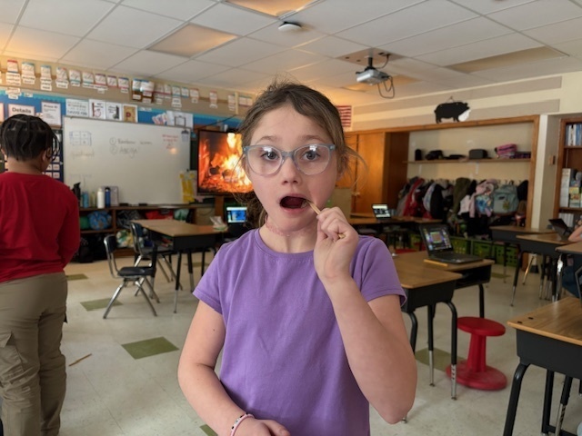 girl swabbing cheek with popsicle stick.