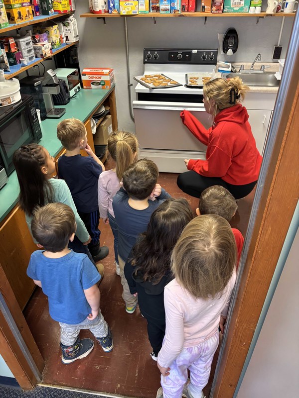 students and teacher making gingerbread man cookies