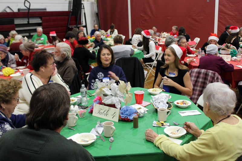 seniors and girl wearing Santa hat singing and chatting at table