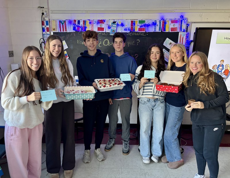 students holding up dishses of food and cards describing them 