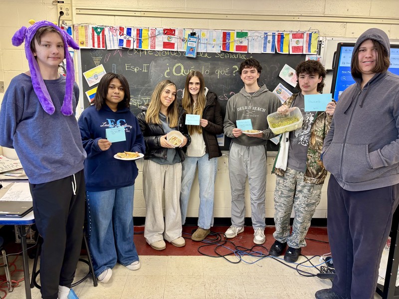 students holding up dishses of food and cards describing them 