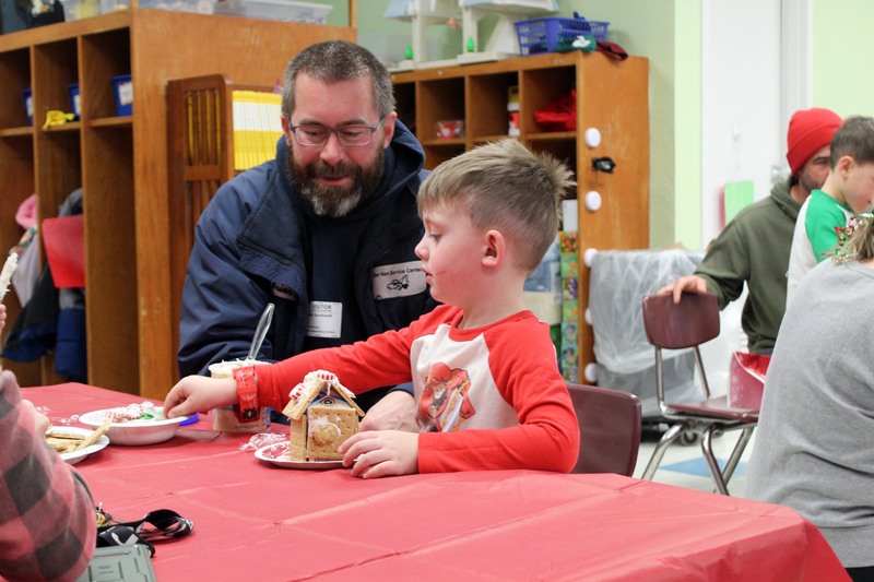 man and boy  making gingerbread houses at table