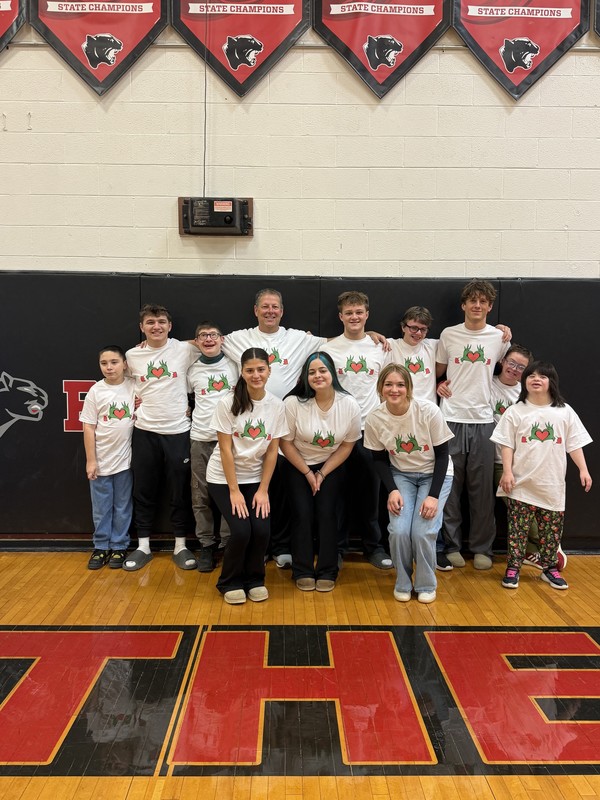 group photo of high schoolers and adults wearing Grinch t-shirts standing in CHS gym