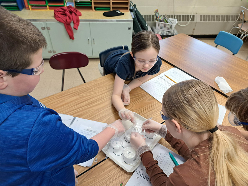 students touching substance in cup