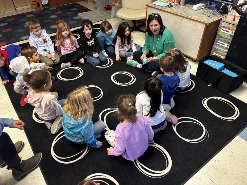 students sitting in circle listening to woman 