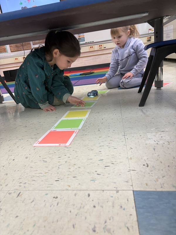 students watching toy car navigate path themade with colored squares