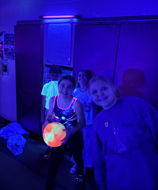 girl holding glowing bowling ball in UV lighting