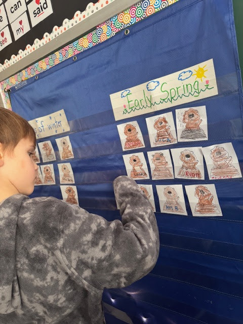 boy placing groundhog card under Early Spring label