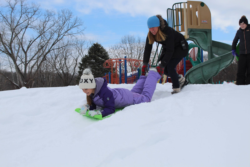 Woman pushing girl on sled