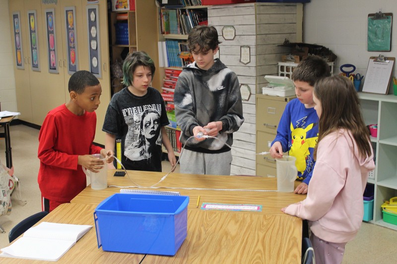 stidents using pump they made to trnferwater from one beaker to another