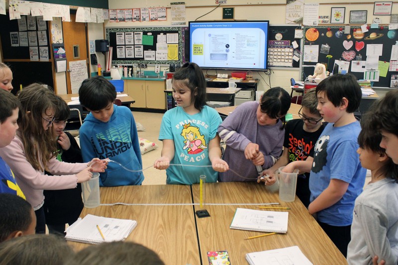 stidents using pump they made to trnferwater from one beaker to another