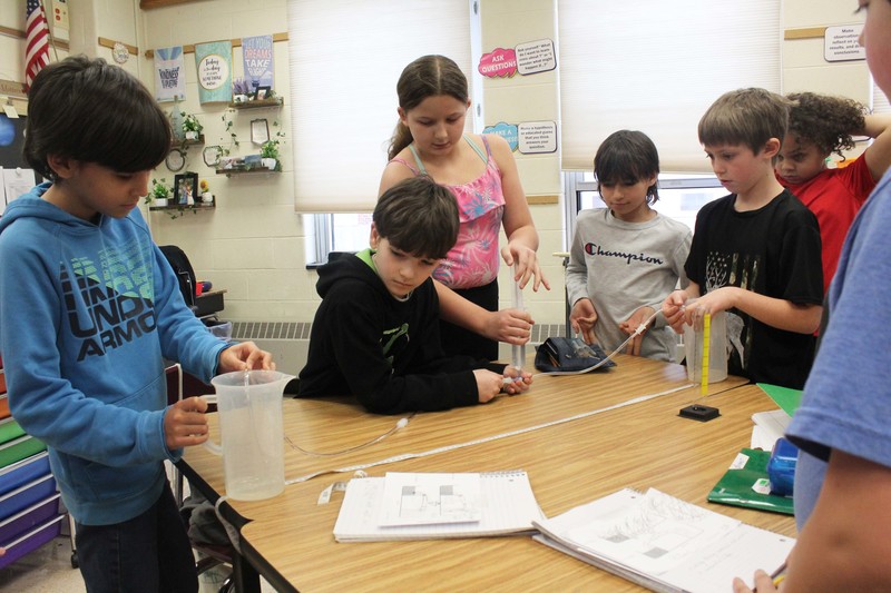 stidents using pump they made to trnferwater from one beaker to another