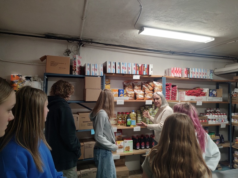 Woman showing students around the food pantry