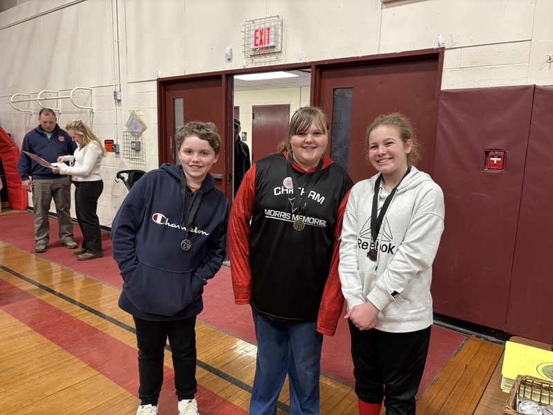 Three girls wearing medals pose for photo