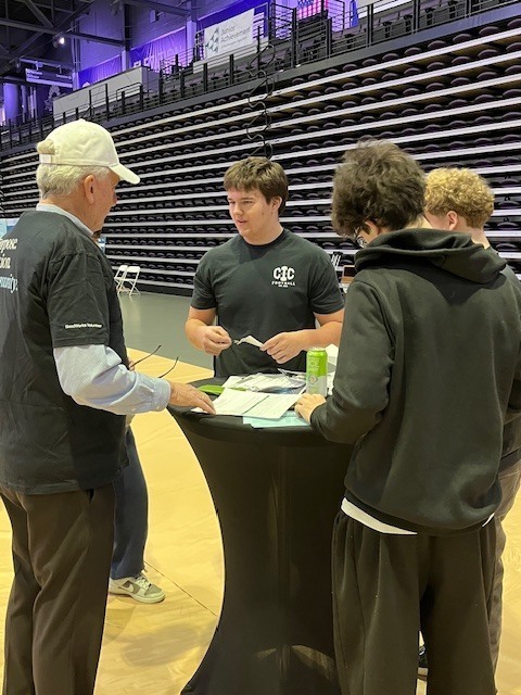 man and students standing around table looking at paper work