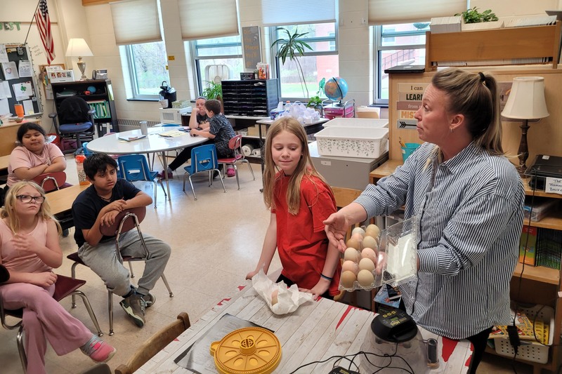 woman showing eggs to classroom of students