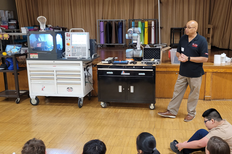 man talking in front of different manufacturing machines