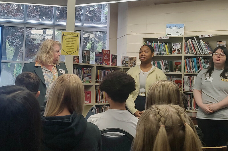 three women talking to audience of students