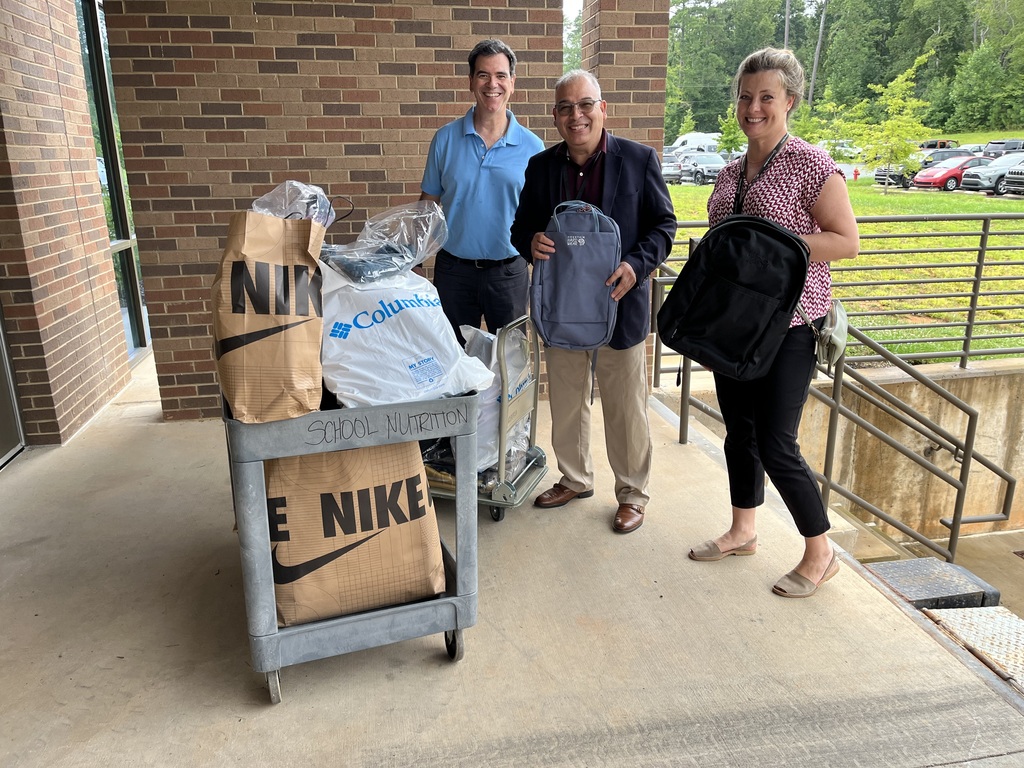 Three staff members picking up backpack donations.