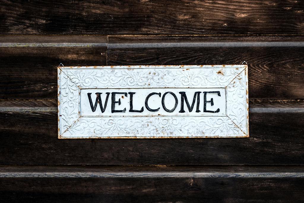 a rustic white sign with the word Welcome on it. 