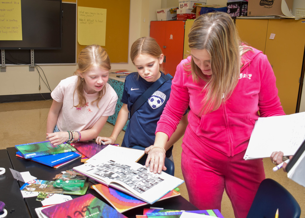 teacher looking at old yearbooks with students
