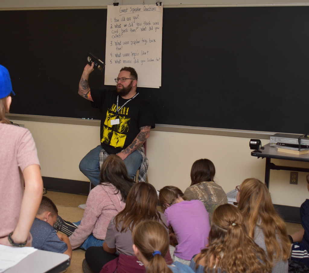 teacher speaking to students with VHS tape in hand