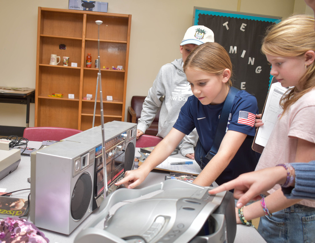 students looking at old boom box radio