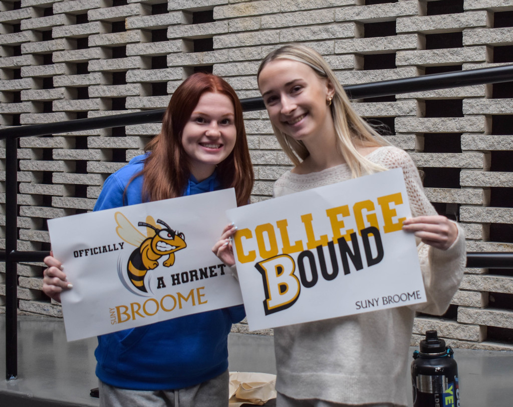 students holding suny broome posters