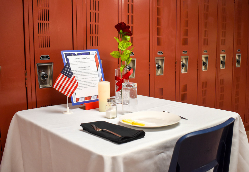 table set up in honor of Veterans with flag, rose, candle, plate and silverware