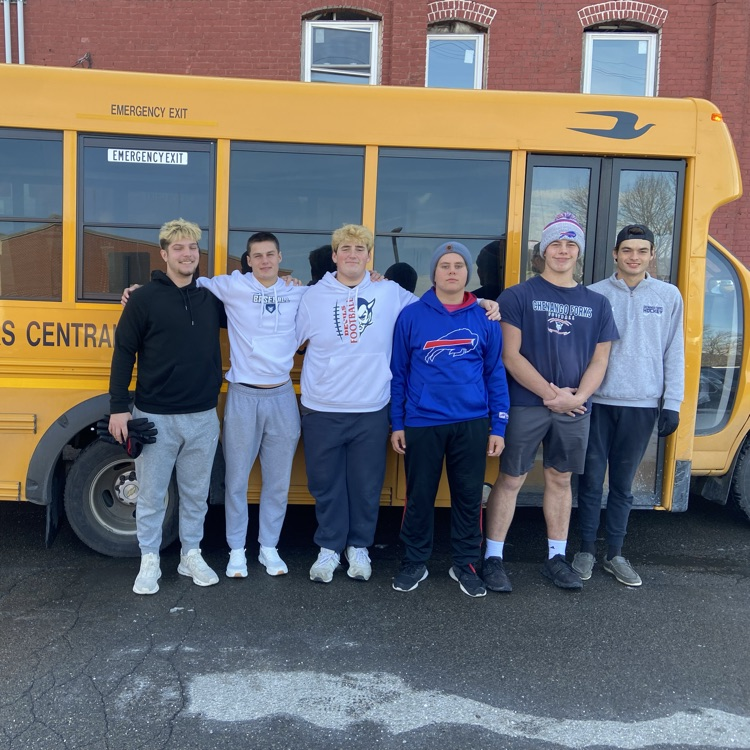 football players standing in front of school bus