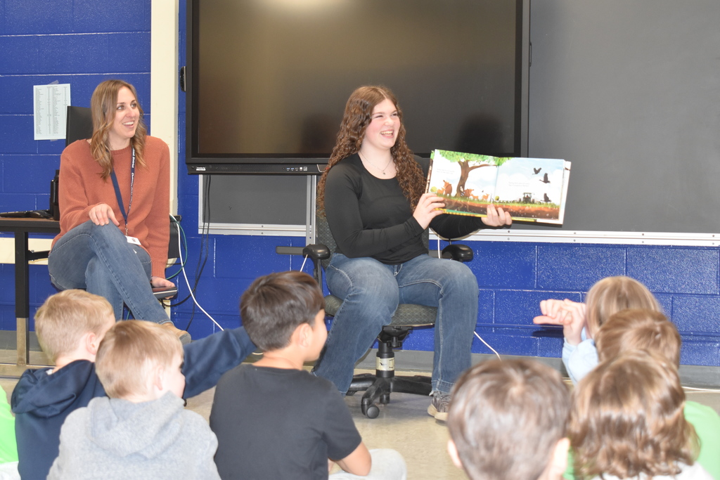 high school student reading to elementary students