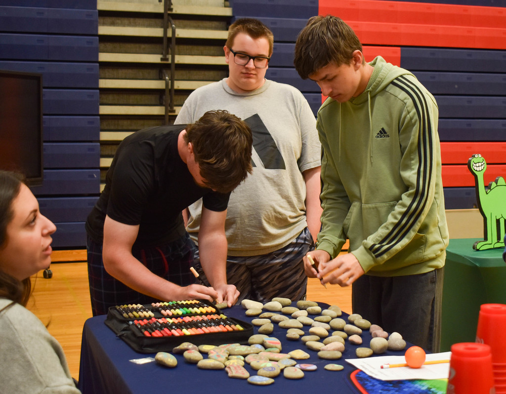 students in gym talking with community organization set up at table