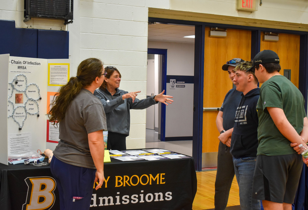students in gym talking with community organization set up at table