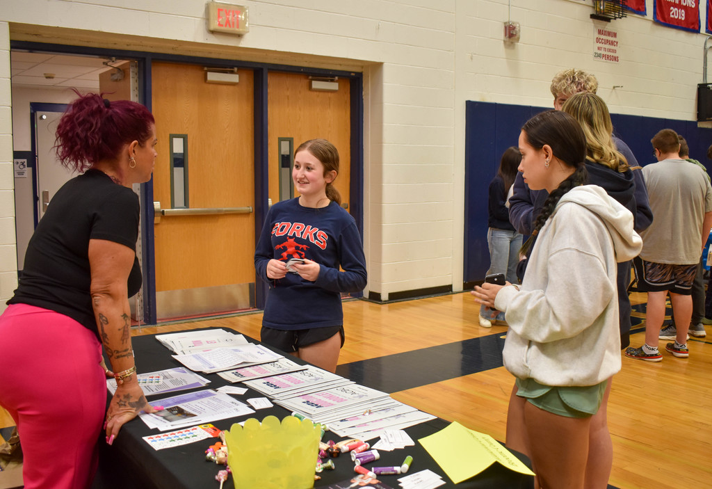 students in gym talking with community organization set up at table