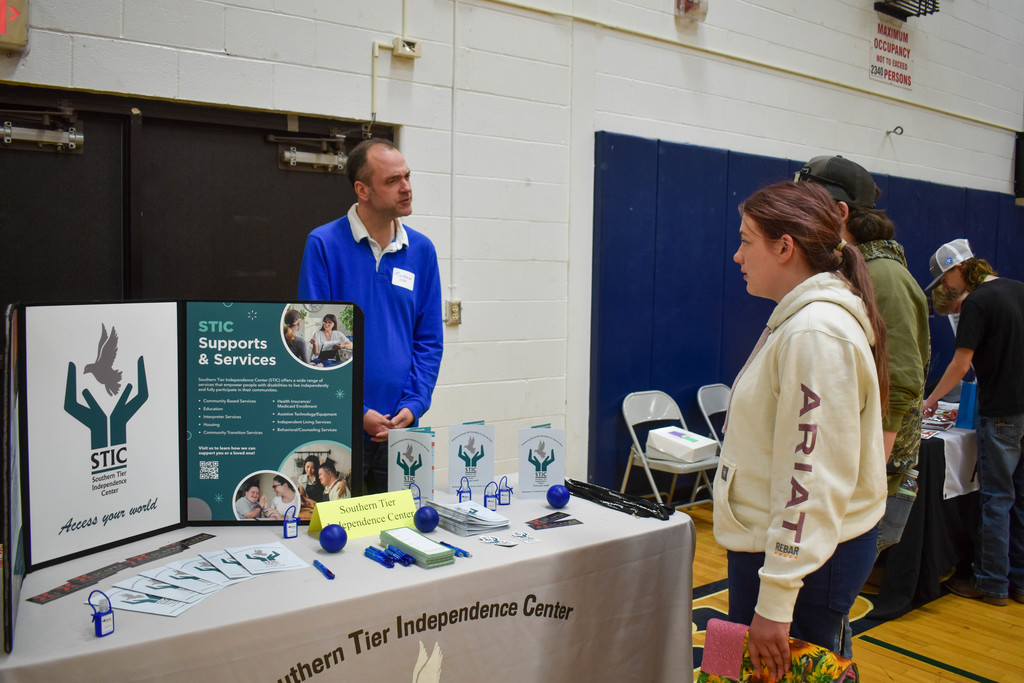 students in gym talking with community organization set up at table