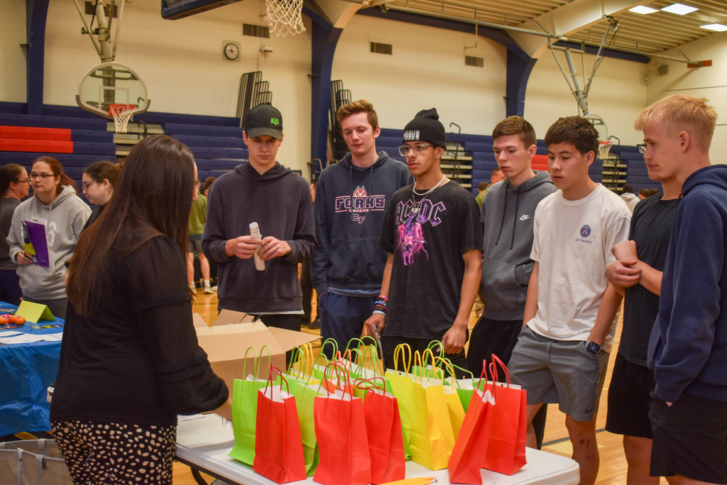 students in gym talking with community organization set up at table