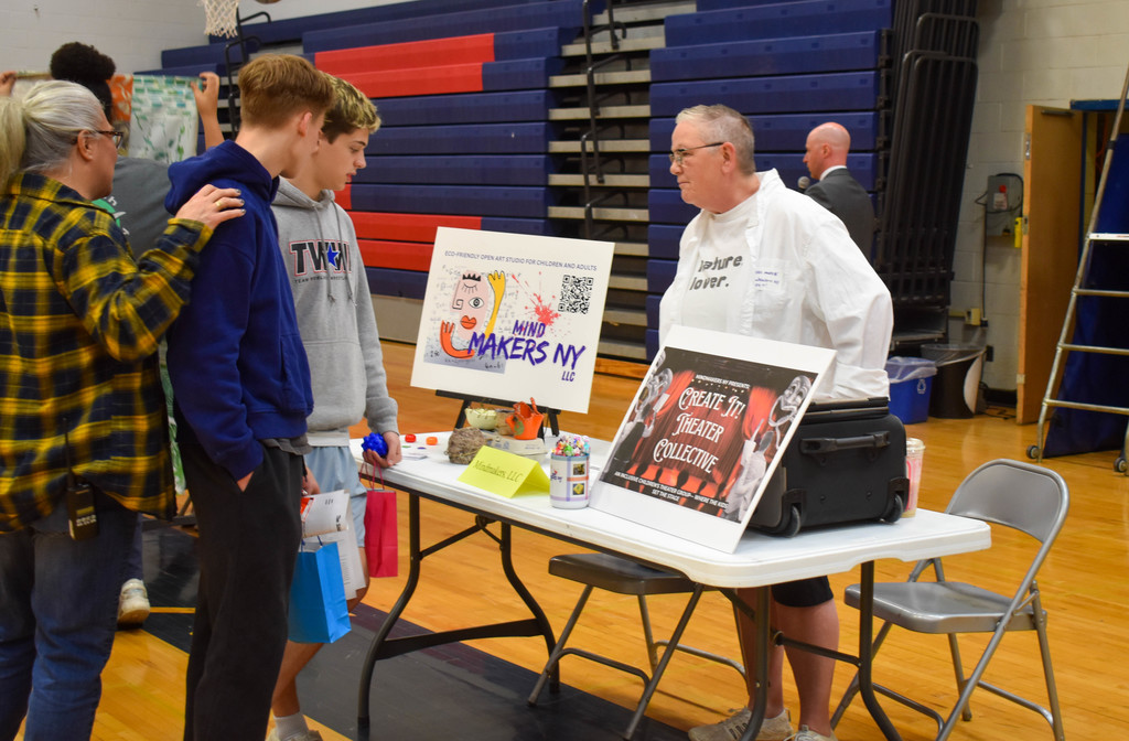 students in gym talking with community organization set up at table