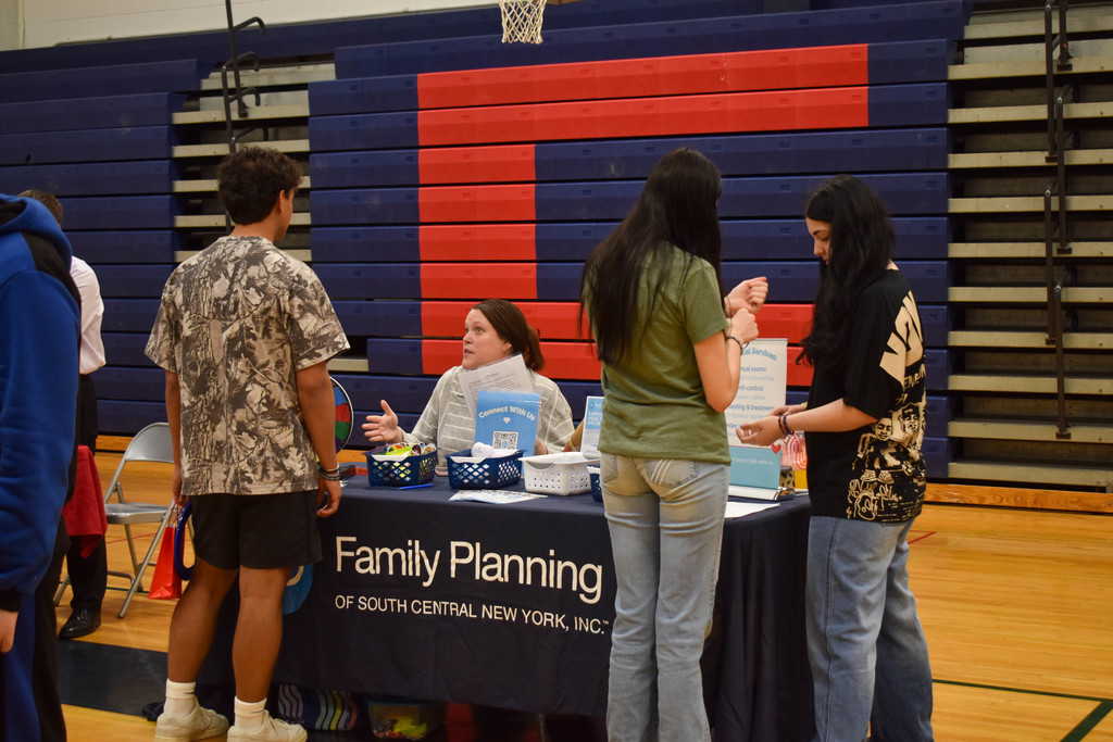 students in gym talking with community organization set up at table