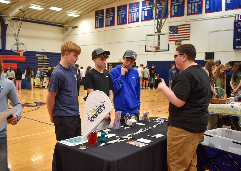 students in gym talking with community organization set up at table