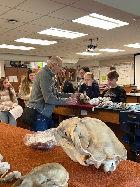 retired teacher with students examining animal skulls