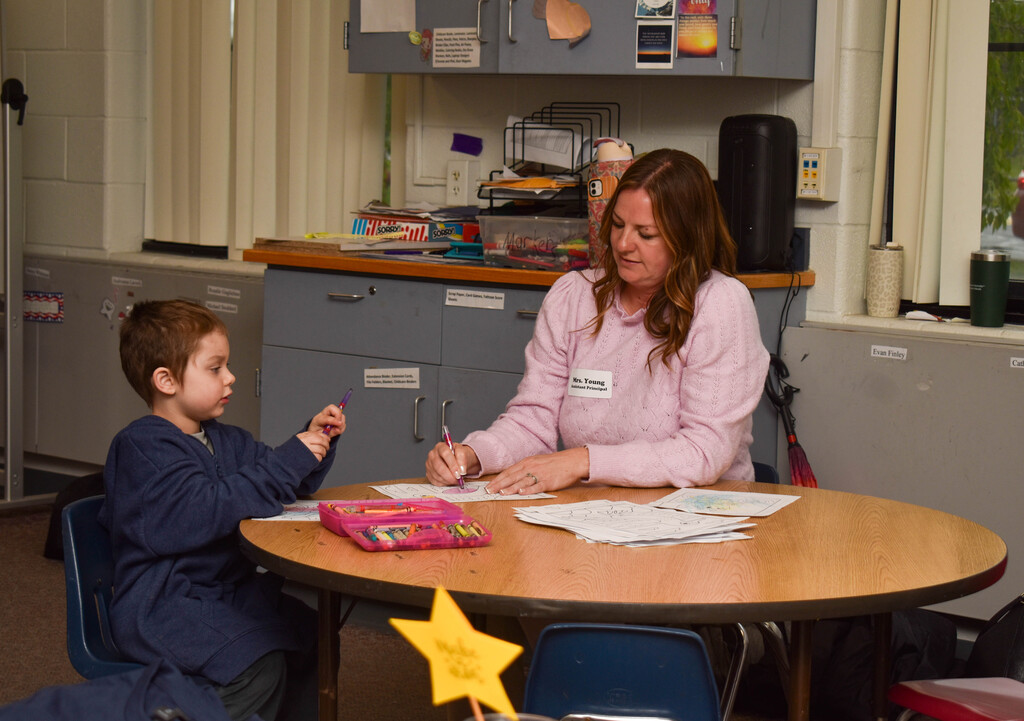 student and teacher coloring at table