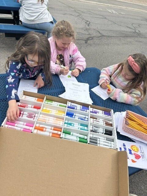 elementary students sitting at table decorating cards