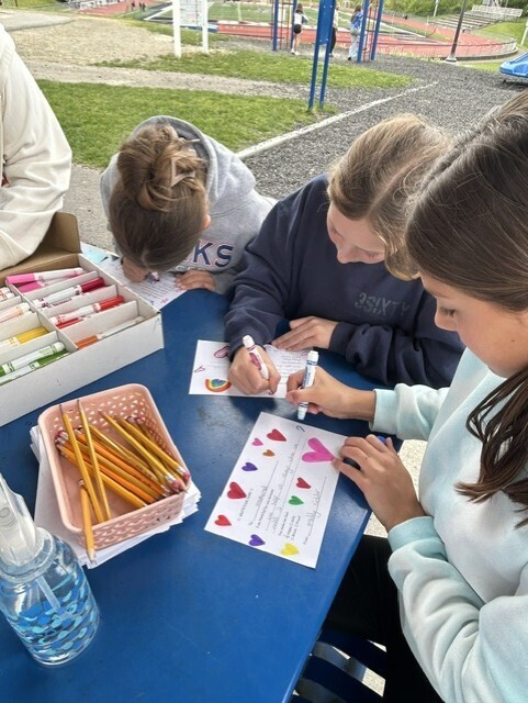 elementary students sitting at table decorating cards