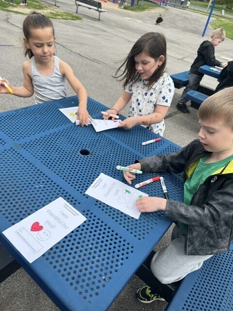 elementary students sitting at table decorating cards