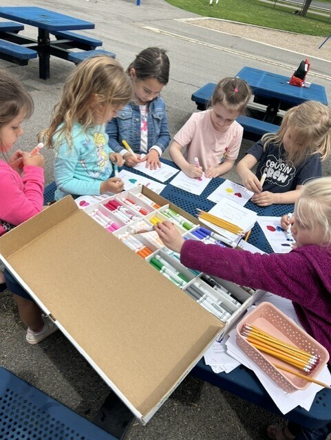 elementary students sitting at table decorating cards