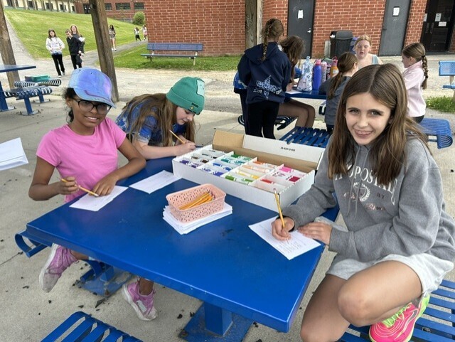 elementary students sitting at table decorating cards
