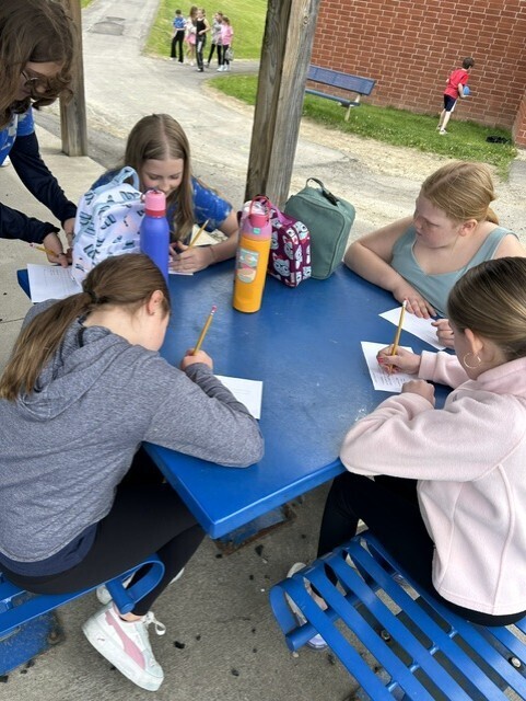 elementary students sitting at table decorating cards