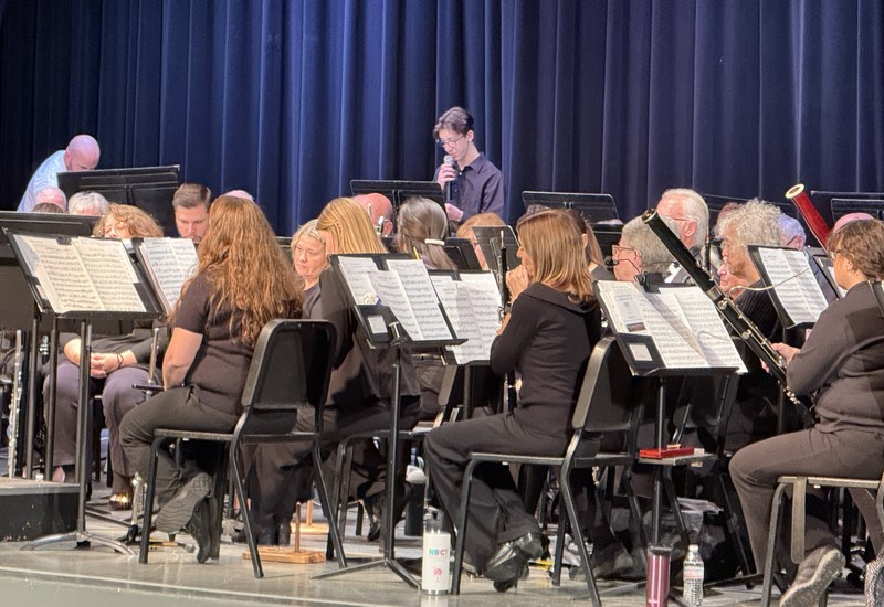 Student and concert band on stage with instruments